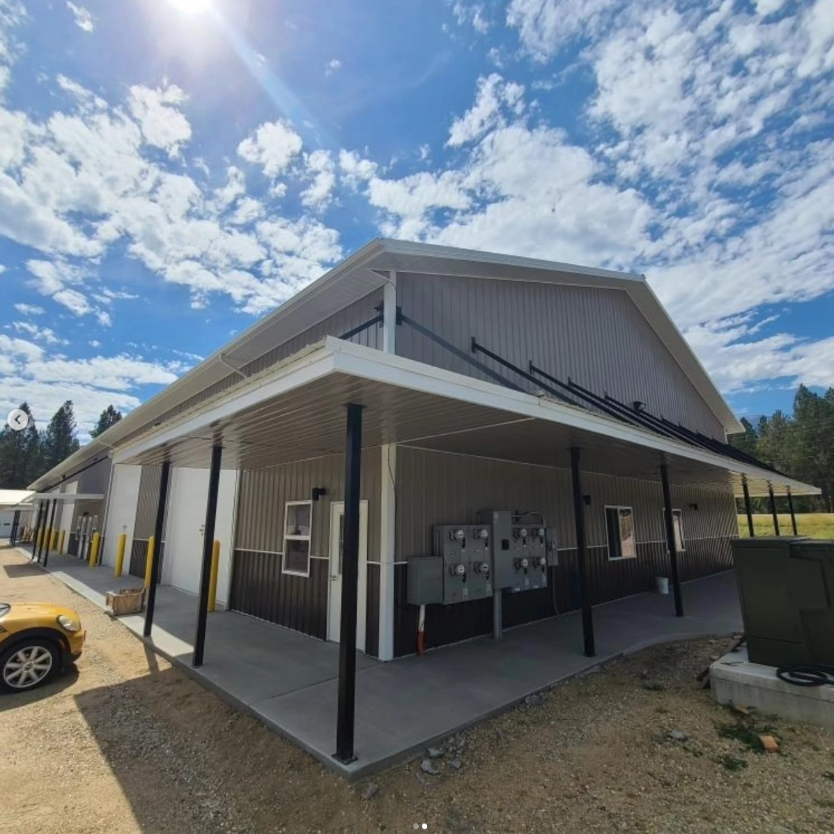 The covered walkway along a Bitterroot Industrial building, with unit entries and electrical meters under a bright Montana sky.